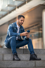 Cosmopolitan handsome man using mobile device and headphones