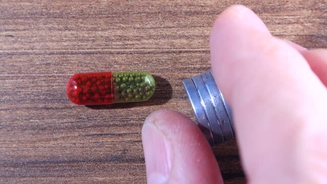 Magnetic field attracts red-green capsules with mini iron balls used to treat chronic blood loss. Iron atoms in supplement far from each other to build ferromagnetic domain but still stick to a magnet