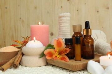 Different aromatherapy products and burning candles on table
