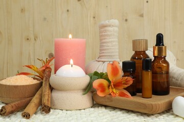 Different aromatherapy products and burning candles on table