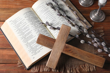 Cross, Bible and willow branches on wooden table, flat lay