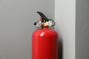One fire extinguisher near grey wall indoors