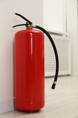 Obraz premium Fire extinguisher on floor near light wall indoors