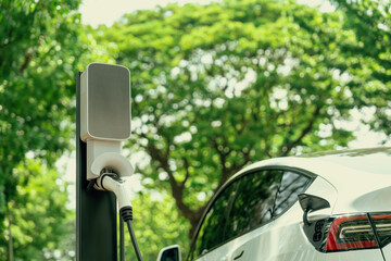 EV electric vehicle recharging battery from EV charging station in national park or outdoor forest...