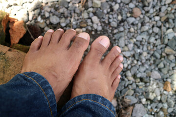 a pair of men legs, dark brown in color. around thirty years old. gravel background