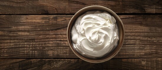 Sour cream displayed in a bowl on a wooden table, as seen from above with space for text.