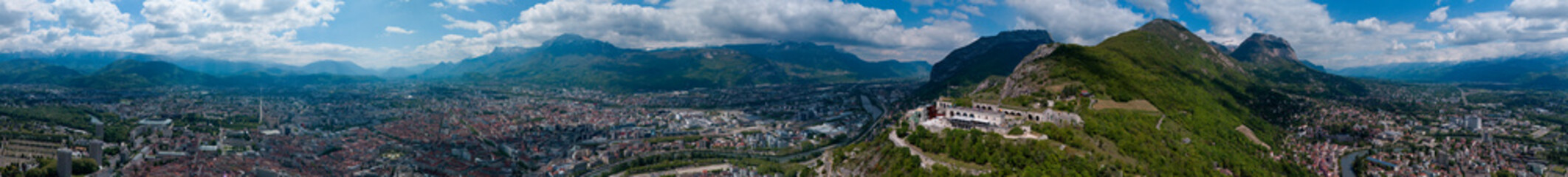 Fototapeta na wymiar Aerial view of Grenoble's Bastille fort, city skyline crossed by the river and surrounded by mountains. France