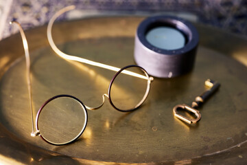 Glasses on a tray. Some old circular glass glasses, next to an old key and a small candle
