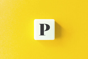 Capital Letter P. Text on Block Letter Tiles against Yellow Background.