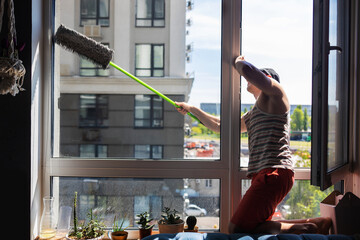 Young man cleaning window with brush at home. Housework concept.