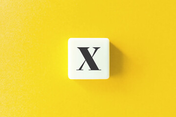 Capital Letter X. Text on Block Letter Tiles against Yellow Background.