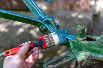 Einen alten Pflug mit Farbe gegen Rost streichen und restaurieren. 