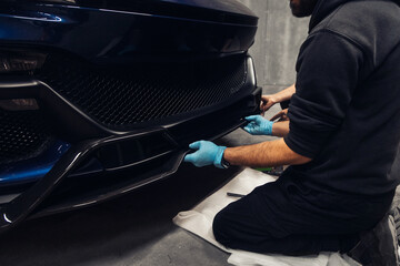 A mechanic installs a carbon fiber car part in a tuning workshop
