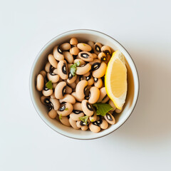 Bowl of black-eyed peas on a pristine white table, with a lemon wedge on the side. Concept of cooking blogs, nutrition guides, and health-focused articles