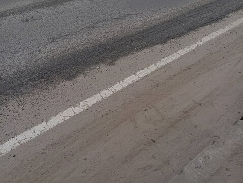 Solid white line on old road surface. Road markings on an asphalt road.