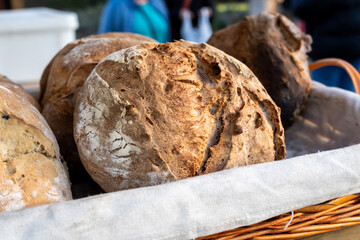 A basket of bread with a white cloth underneath. The bread is brown and has a crust. There are...
