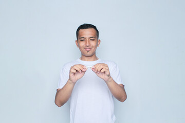 Asian young man wearing a white t-shirt cuts a cigarette in commemoration of world no tobacco day.