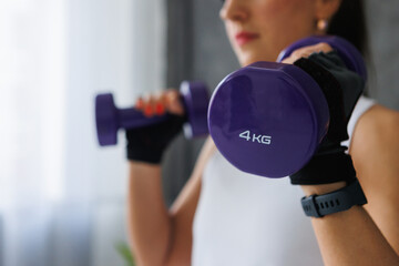 Watch as the woman holds two purple dumbbells in her hands, wearing sportswear and personal...
