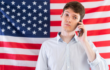 Young guy talking on phone on background of USA flag