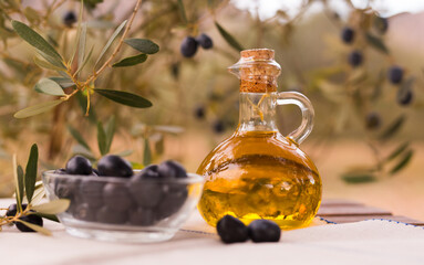 Still life of olives and oil on a table against a background of olive trees - 803356279