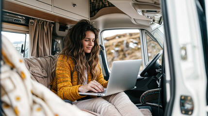 Young woman working on her laptop in a cozy camper van