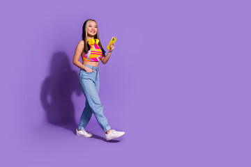 Photo of adorable pretty cute girl wear stylish clothes going empty space isolated on purple color background
