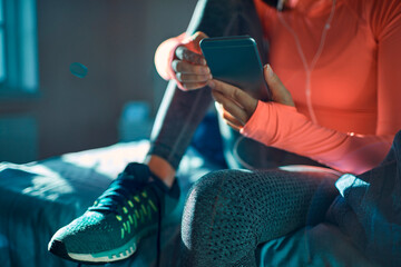 Fitness woman selecting music on smartphone before workout