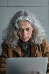 frustrated senior woman with gray hair using laptop. High quality photo