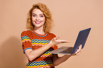 Photo portrait of lovely young lady hold point netbook dressed stylish striped garment isolated on beige color background