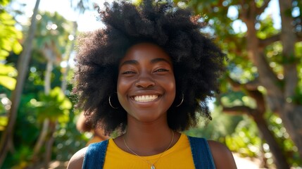   Close-up of a person in a yellow shirt, wearing a necklace and smiling, with a tree in the background