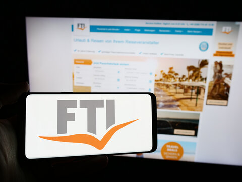Stuttgart, Germany - 04-15-2024: Person holding smartphone with logo of German travel company FTI Touristik GmbH in front of website. Focus on phone display.