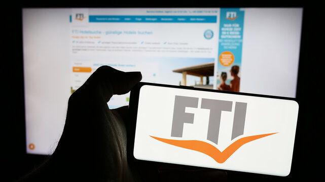 Stuttgart, Germany - 04-15-2024: Person holding mobile phone with logo of German travel company FTI Touristik GmbH in front of business web page. Focus on phone display.