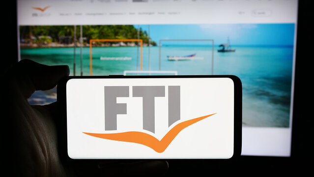 Stuttgart, Germany - 04-15-2024: Person holding cellphone with logo of German travel company FTI Touristik GmbH in front of business webpage. Focus on phone display.