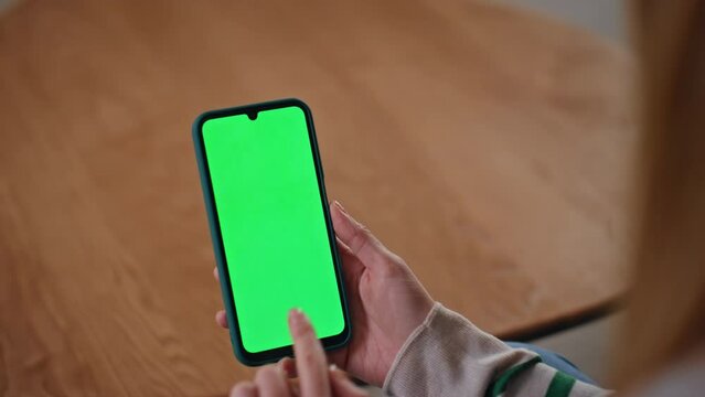 Girl hands swiping mockup cellphone at apartment close up. Unrecognizable woman