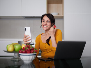 Woman make a pictures of strawberries at home kitchen
