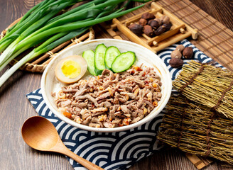 Roast duck rice with egg, cucumber, spring onion, spoon and chopsticks served in bowl isolated on napkin side view on table taiwan food