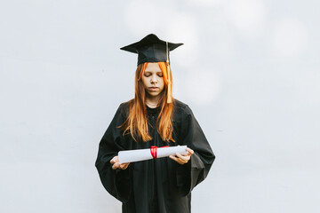 teenage girl in clothes of a graduate coat and cap celebrates high school or  junior year...