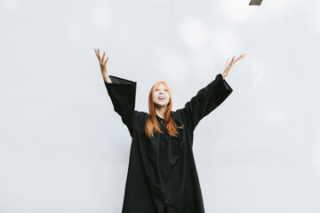 teenage girl in clothes of a graduate coat and cap celebrates high school or  junior year...