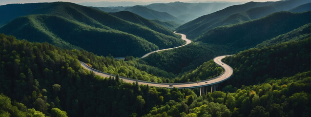 Aerial panorama, snaking roadway amidst sprawling dark green mountain forest