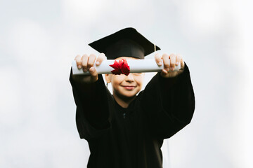 teenage boy in clothes of a graduate coat and cap celebrates high school or  junior year graduation...