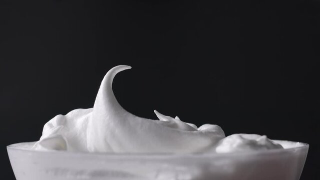 Chef mixes whipped egg whites with sugar and stirs with a spoon, dessert preparation process, close-up of food