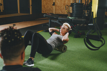 Athlete man and woman performing exercises for back with foam roller