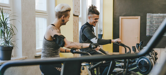 Male sport trainer helping young woman riding a exercise bike during an exercise class
