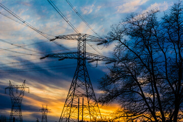Power grid transmission towers network against blue sky at sunset