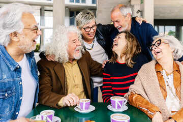 Joyful group of senior friends having fun drinking coffee at cafeteria bar. Baby boomer generation...