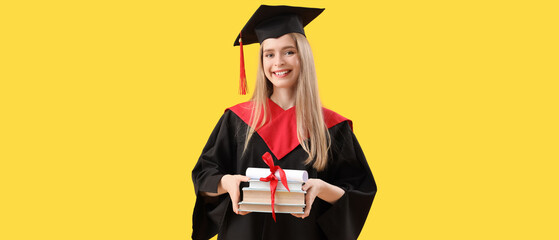 Female graduate student with diploma and books on yellow background