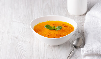 Pumpkin soup on a white wooden table, with copy space for text