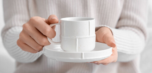 Woman holding saucer with cup of coffee, closeup