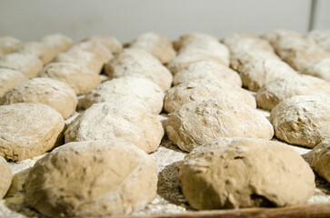Handcrafting loaves of bread dough. Process occurs in a bakery. The dough is kneaded by warm hands.