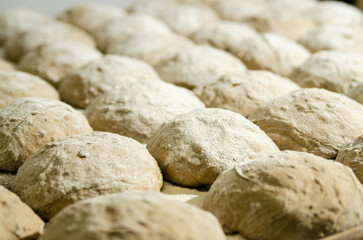 Handcrafting loaves of bread dough. Process occurs in a bakery. The dough is kneaded by warm hands.